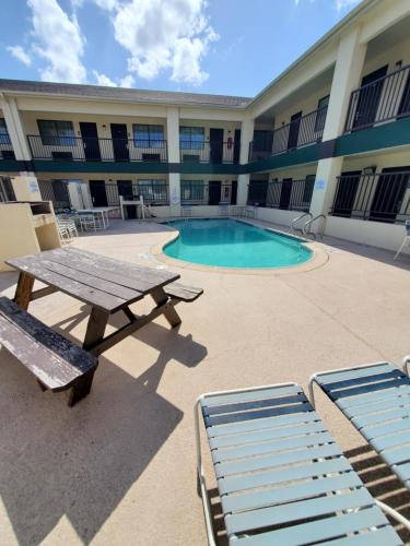 a picnic table and a pool in front of a building at Deluxe Inn and Suites in Raymondville