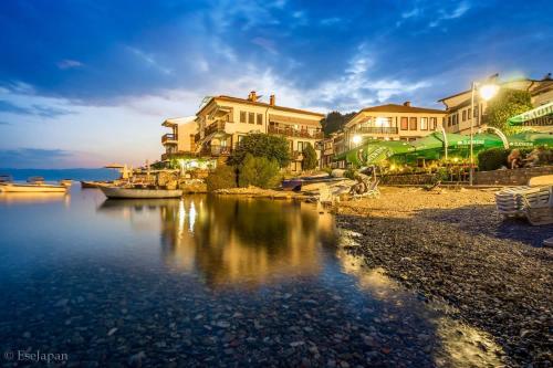 un groupe de maisons sur la rive d'une masse d'eau dans l'établissement Villa Afrodita Lake View, à Ohrid