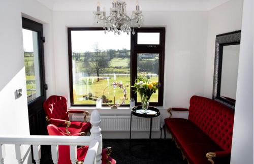a living room with two red chairs and a table and a window at Ashwoods House in Enniskillen