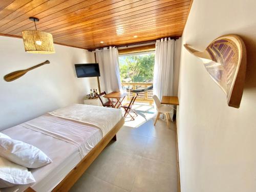 a bedroom with a bed and a table and a window at Pousada Belas Águas in Praia de Araçatiba