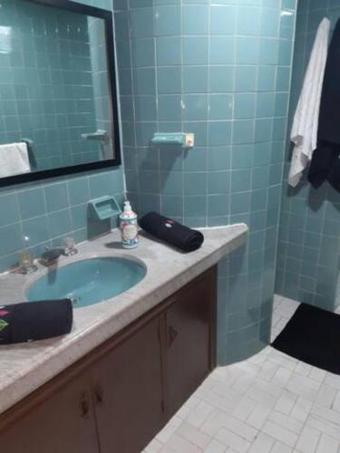 Baño azul con lavabo y espejo en Habitacion con baño compatido en casa de familia en Corferias, Quinta Paredes, Embajada Americana, en Bogotá