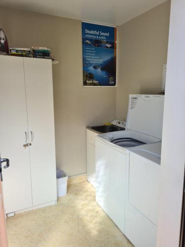 a kitchen with white cabinets and a washer and dryer at Arran Motel in Te Anau