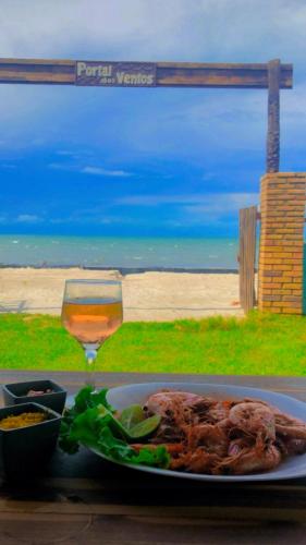 a plate of food and a glass of wine on a table at Restaurante & Pousada Portal dos Ventos in Icapuí