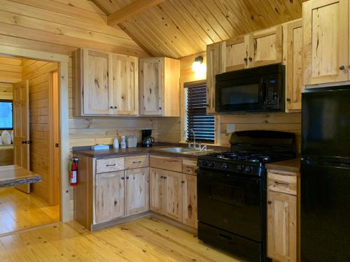 a kitchen with wooden cabinets and a black stove top oven at Waterfront Inn Mackinaw City in Mackinaw City