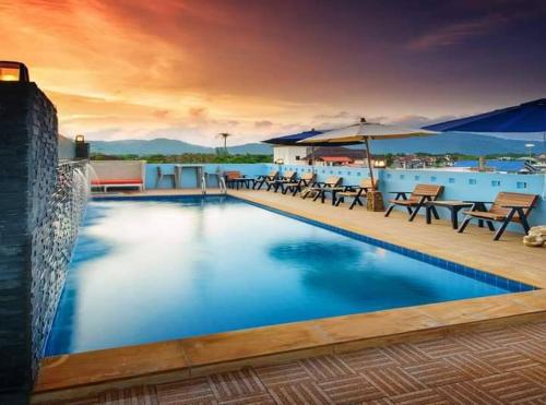 una grande piscina con sedie e ombrellone di The Cheetar Hotel a Amphoe Kathu