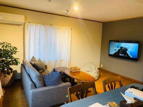 a living room with a couch and a tv on the wall at 熱海天海ヴィラ/ Atami Tenkai Villa in Atami