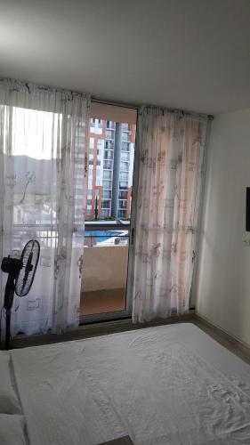 a bedroom with a bed and a large window at Apartamento en Reserva del Peñon Girardot. in Girardot