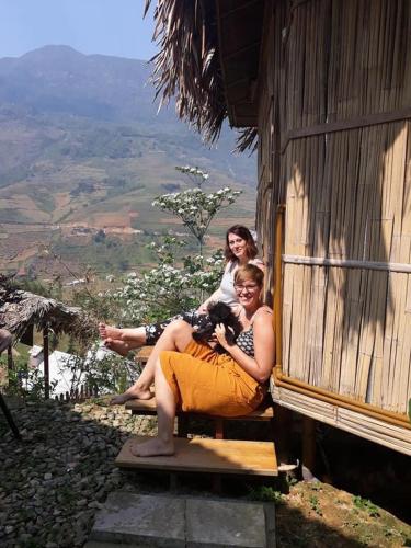 two women sitting on the porch of a building at Eco Hills Homestay in Sa Pa