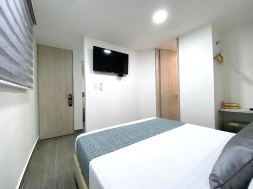 a bedroom with a white bed and a flat screen tv at Seven Inn Hotel in Medellín
