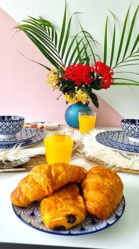 a table with a plate of pastries and glasses of orange juice at Grand studio avec Jardin, Wifi et parking privé in Fort-de-France