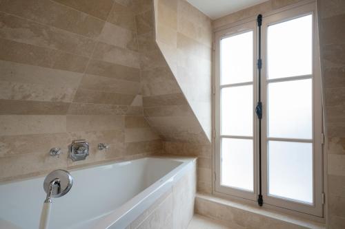 a bathroom with a tub and a window at Hotel Saint-Louis en L'Isle - Notre-Dame in Paris