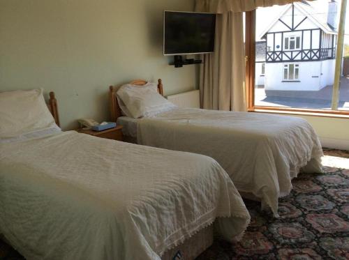 two beds in a hotel room with a window at Room in Guest room - Orchard Manor, Fore Street Probus, Tr24ly in Truro