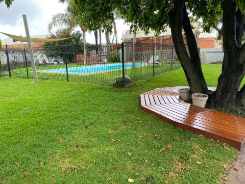 a wooden bench sitting next to a tree in a park at Cobram Colonial Motor Inn in Cobram