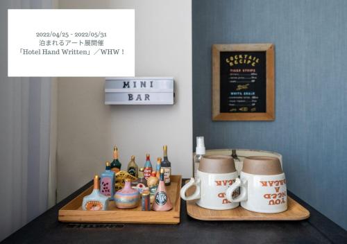 a table with two serving trays with bottles and mugs at Hotel Graphy Nezu in Tokyo