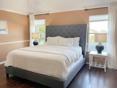 a bedroom with a large bed and two windows at Modern Chic Home in Channelview