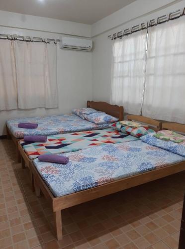 two twin beds in a bedroom with curtains at Sanctuary Transient House in Bacolod