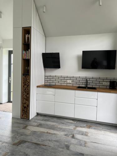 a kitchen with white cabinets and a flat screen tv on a wall at Utriai Guest Place in Utriai