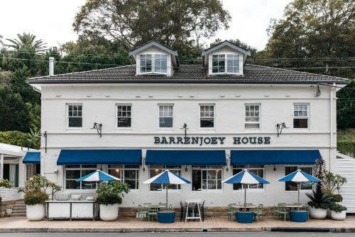 棕榈滩Barrenjoey House的前面有蓝色伞的白色建筑