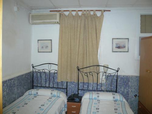 2 letti singoli in una camera da letto con piastrelle blu di Pensión Campoy a Murcia