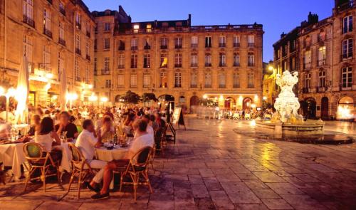 un gruppo di persone seduti ai tavoli in una strada di notte di Au Cocon d'Ornon - Top Location Bordeaux a Villenave-d'Ornon
