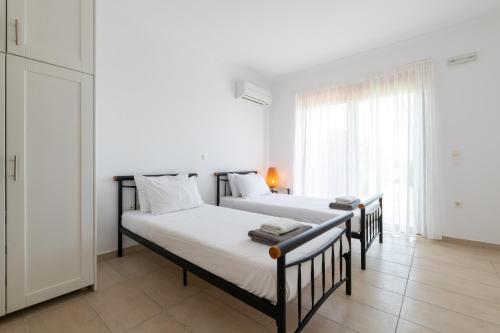 2 Betten in einem weißen Zimmer mit Fenster in der Unterkunft Villa Milena with private pool, Vlicha beach Lindos in Lindos