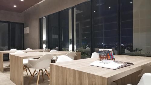 a dining room with white chairs and tables and windows at Lumi Tropicana in Petaling Jaya