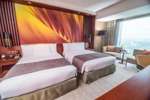 a hotel room with two beds and a living room at Marco Polo Ortigas Manila in Manila