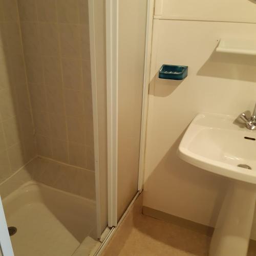 une salle de bain blanche avec un lavabo et une douche dans l'établissement ferme de Bournazel, à Bournazel