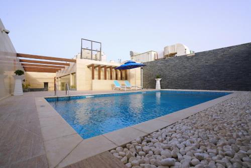 una piscina de agua azul frente a un edificio en Al Aseel Hotel, en Doha