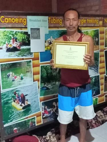a man holding up a framed sign in front of a wall at Wassana Camp & Khai jungle experience in Ban Kraison