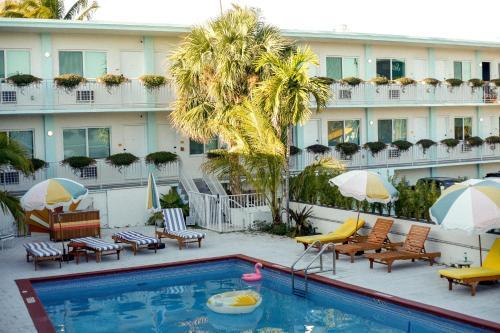 a hotel pool with chairs and umbrellas and a hotel at Selina Gold Dust in Miami