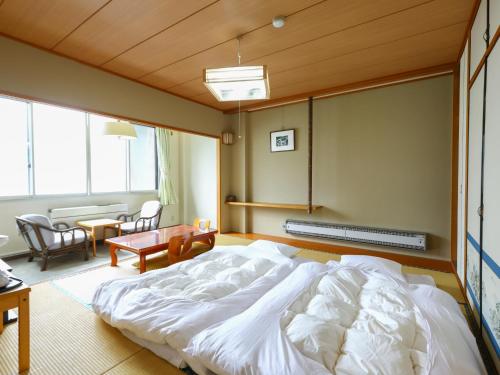 a hotel room with a bed, chair, and nightstand at Hotel Yudanaka in Yamanouchi
