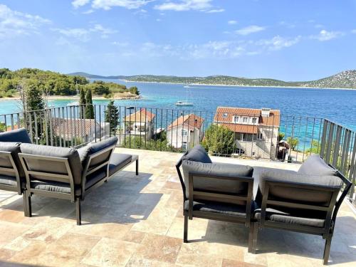 um pátio com cadeiras e vista para a água em Spacious new villa with pool above the pristine beach - FIRST SEASON PRICING!!! em Prvic Sepurine