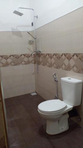 a bathroom with a white toilet and a shower at Nageran Homestay in Dambulla