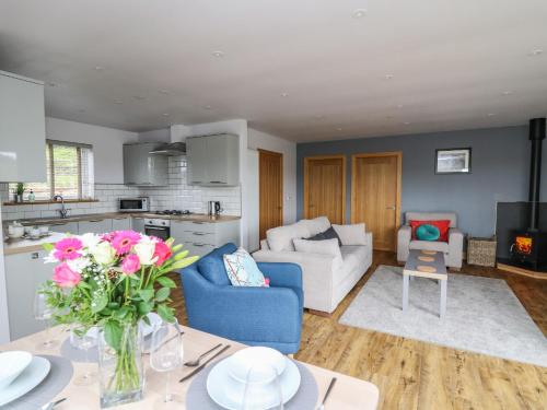 a kitchen and living room with a table with flowers at Llyn Cae Ty Nant Fishery Holiday Let in Lampeter