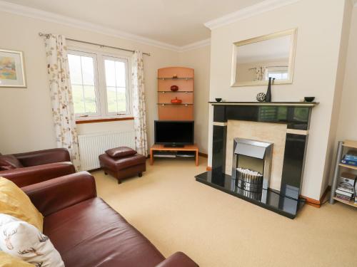 a living room with a couch and a fireplace at Brae Mhor Cottage in Fort William