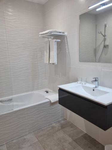 ein Badezimmer mit einem Waschbecken, einer Badewanne und einem Spiegel in der Unterkunft HOTEL AMBEILLE in Collioure