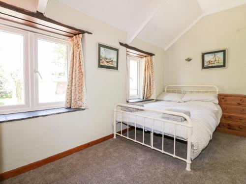 a bedroom with a bed and two windows at Little Trespettigue in Launceston