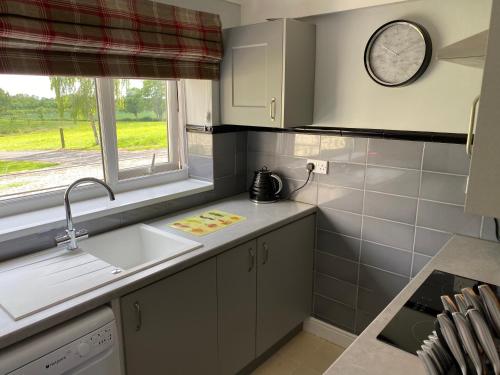 a kitchen with a sink and a clock on the wall at Beck Hill Cottage In Brandsby in York