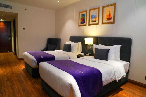 a hotel room with two beds and a chair at Indigo Heights Hotel & Suites in Lahore