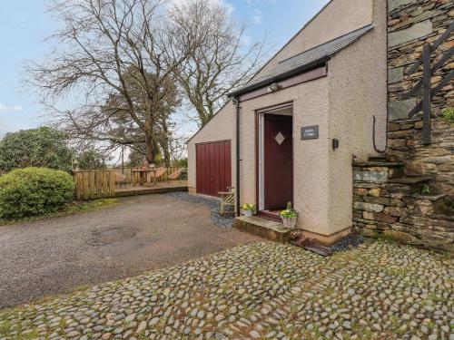 a brick house with a red door and a driveway at The Stables in Millom