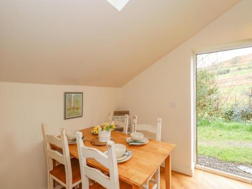 a dining room with a wooden table and a window at The Stables in Millom