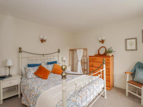 a bedroom with a white bed with orange pillows at The Stables in Millom