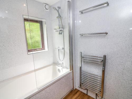 a bathroom with a shower and a tub and a window at The Coach House in Carnforth
