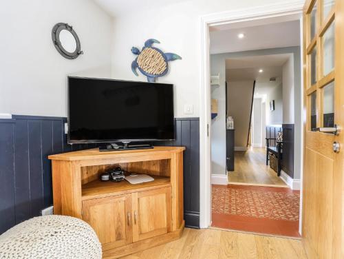 a flat screen tv on a wooden stand in a living room at Dolwaenydd in Llanfairpwllgwyngyll