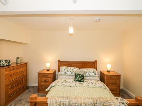 a bedroom with a bed with two dressers and two candles at The Old Cow Shed in Banwell