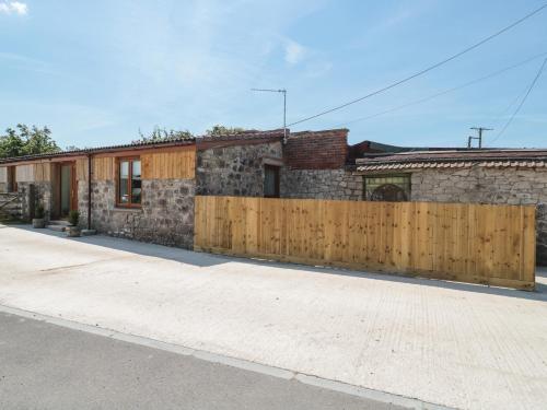 a house with a wooden fence in front of it at The Old Cow Shed in Banwell