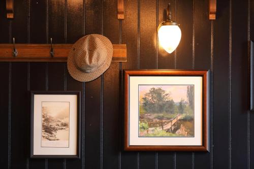 a wall with two pictures and a hat on it at Pont y Pair Inn in Betws-y-coed