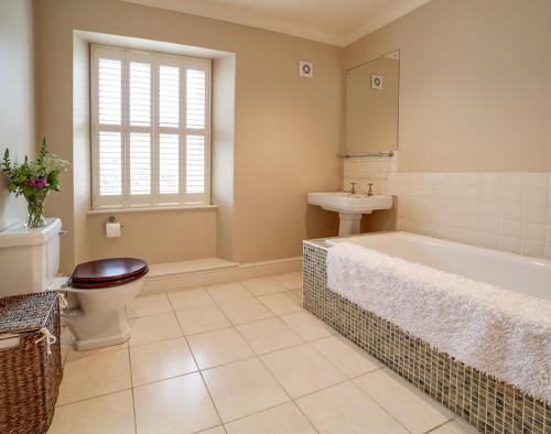 a bathroom with a tub and a toilet and a sink at Worthy House in Polzeath