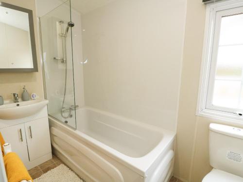 a white bathroom with a shower and a sink at Lakeside View in Kings Lynn